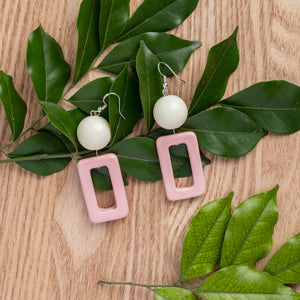 pink hollow rectangle with white bead handcrafted earrings on wooden background